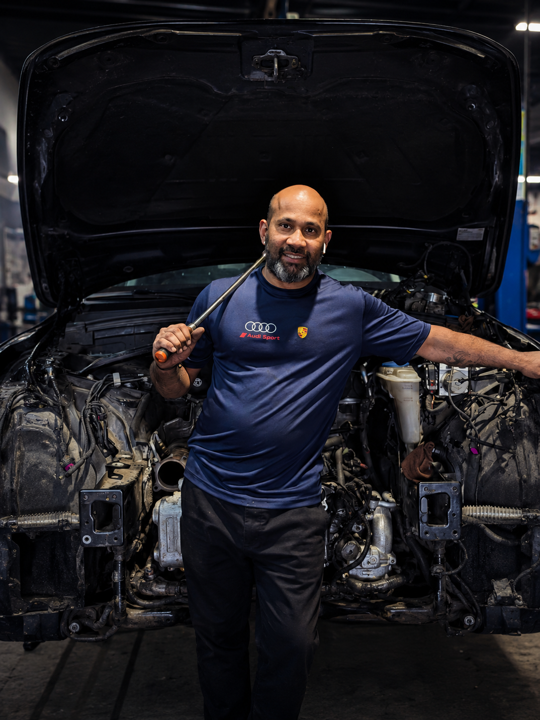 Certified mechanic working under the hood with a wrench