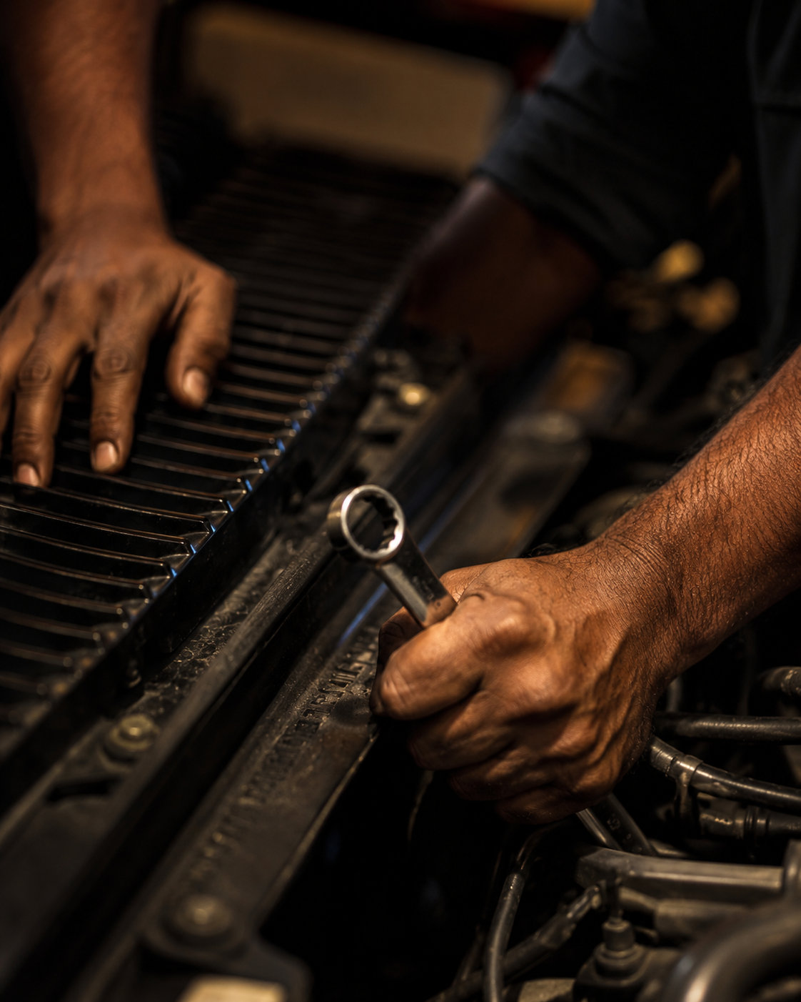 Certified mechanic working under the hood with a wrench